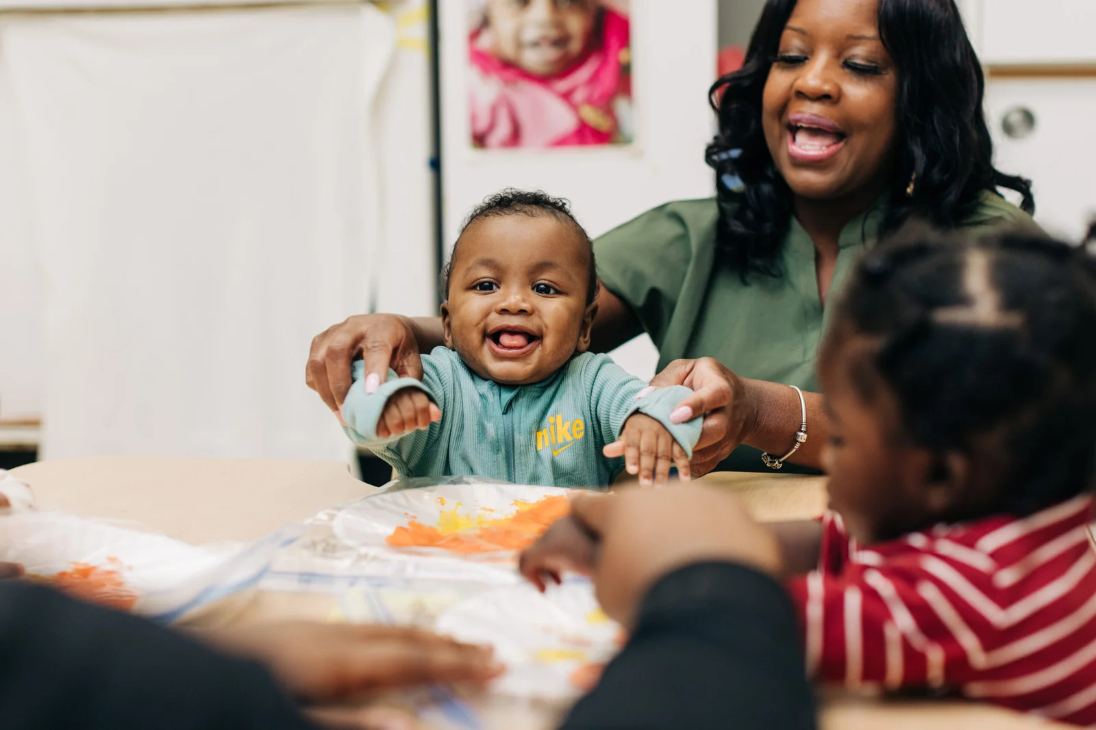 Young infant and child care teacher doing a painting craft together.